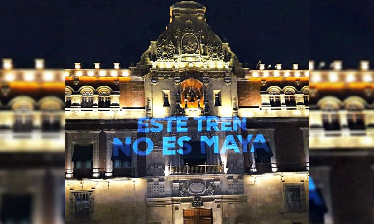 Foto: @VotoXel | Proyectan mensajes de protesta contra el Tren Maya, en Palacio Nacional.