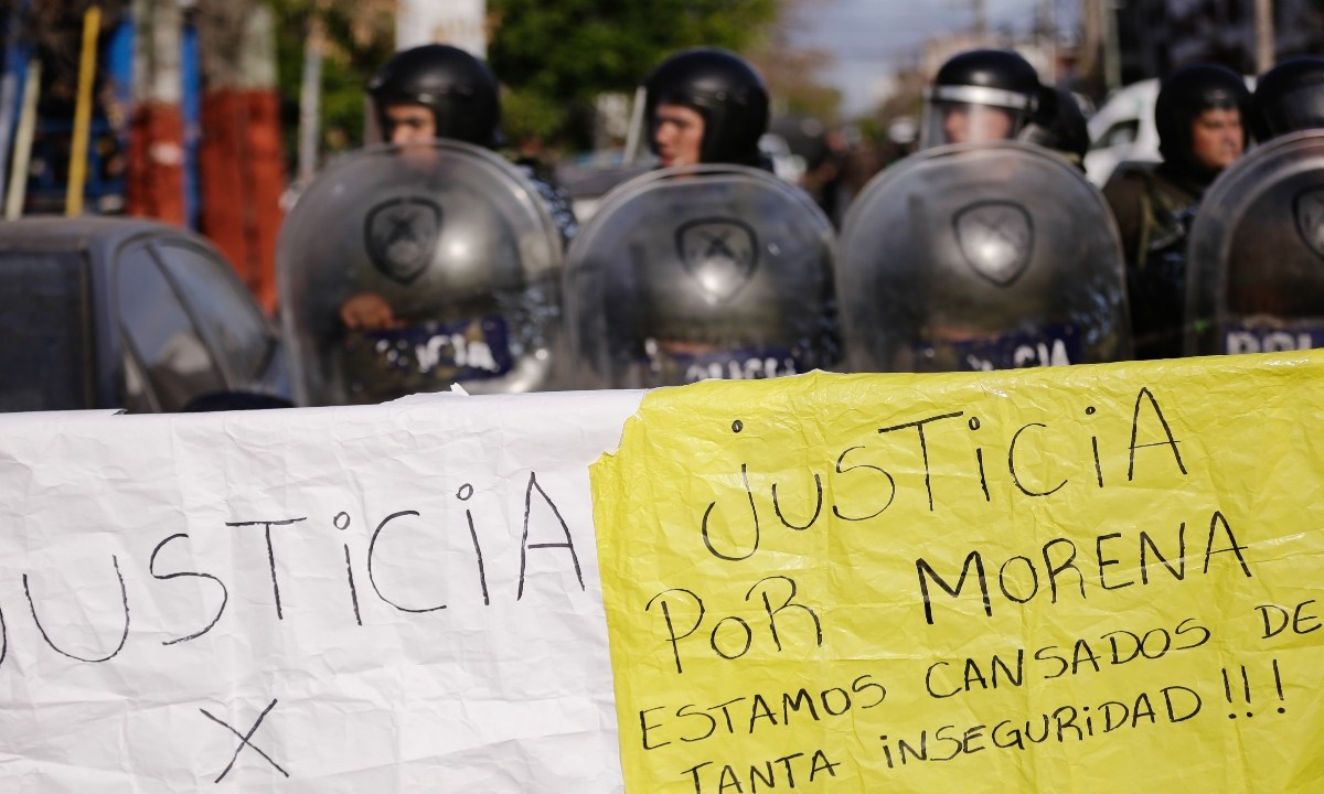Habitantes portaron pancartas ayer con la leyenda "Justicia para Morena, estamos cansados de tanta inseguridad" mientras policías hacen guardia durante una manifestación en Lanús
