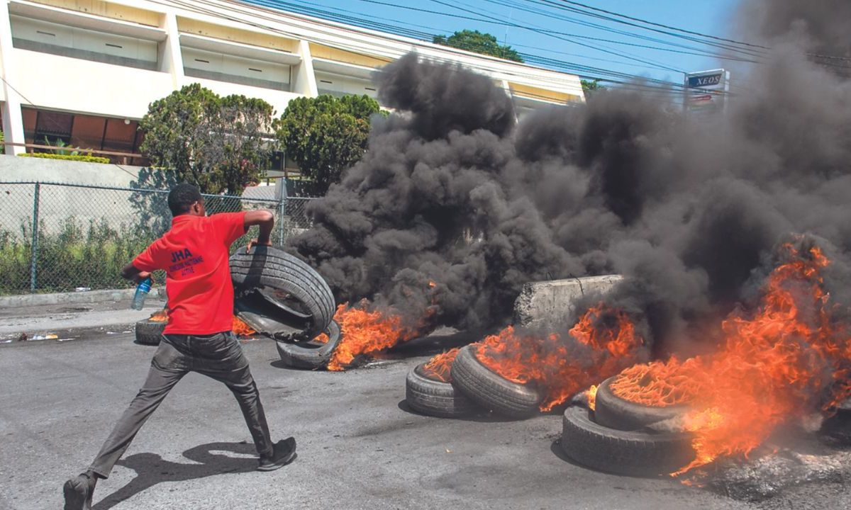 VIOLENCIA. Un poblador quemó neumáticos ayer en la capital Puerto Príncipe durante una manifestación tras la dimisión del gobernante Ariel Henry.