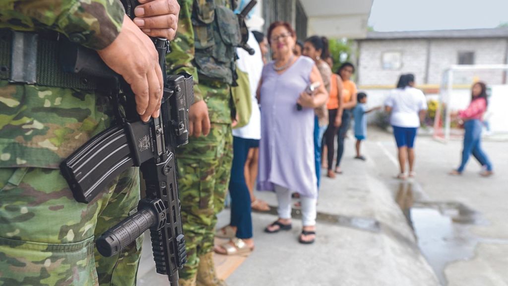 PARTICIPACIÓN. Soldados hacían guardia ayer mientras la gente se formaba para votar, durante una consulta popular sobre medidas más duras contra el crimen organizado, en la provincia de Santa Elena.