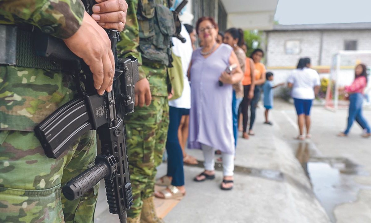 PARTICIPACIÓN. Soldados hacían guardia ayer mientras la gente se formaba para votar, durante una consulta popular sobre medidas más duras contra el crimen organizado, en la provincia de Santa Elena.