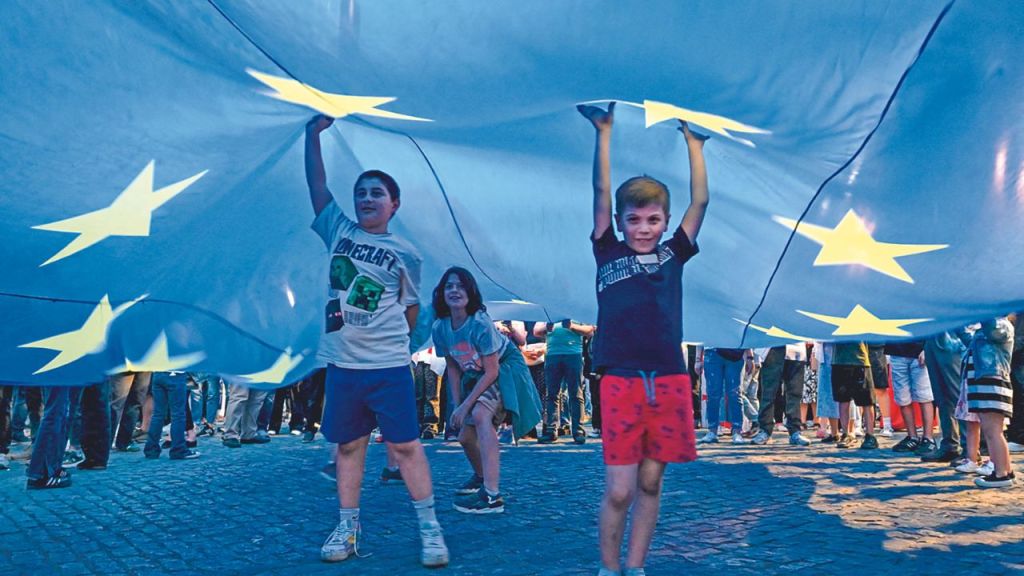 INFANCIA. Menores jugaban bajo una bandera gigante de la Unión Europea mientras manifestantes protestaban contra un controvertido proyecto de ley de "influencia extranjera", en Tiflis, el pasado 28 de abril de 2024.
